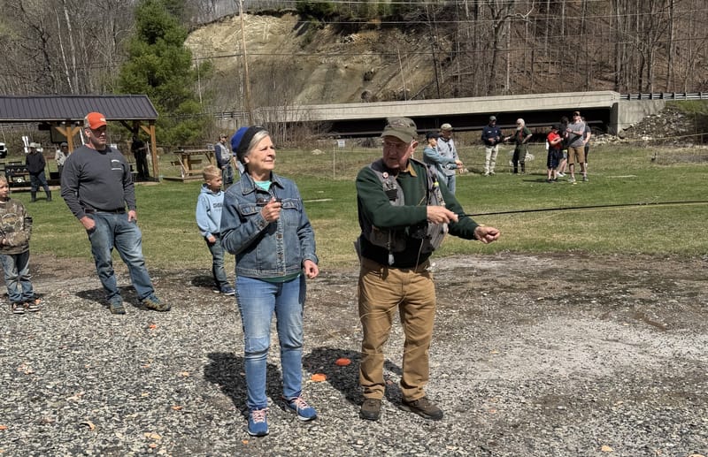 Adults and children practicing fly casting outdoors at the club